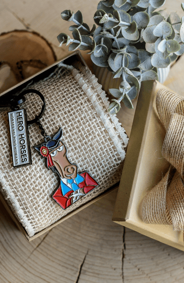 “ A male client lying on a white horse during an equine-facilitated therapy session, assisted by two therapists walking alongside in a sand arena..